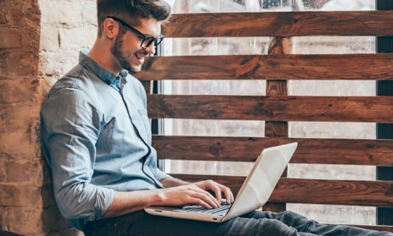 Man on Laptop Sitting by Window