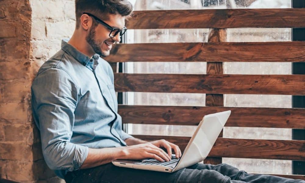 Man on Laptop Sitting by Window