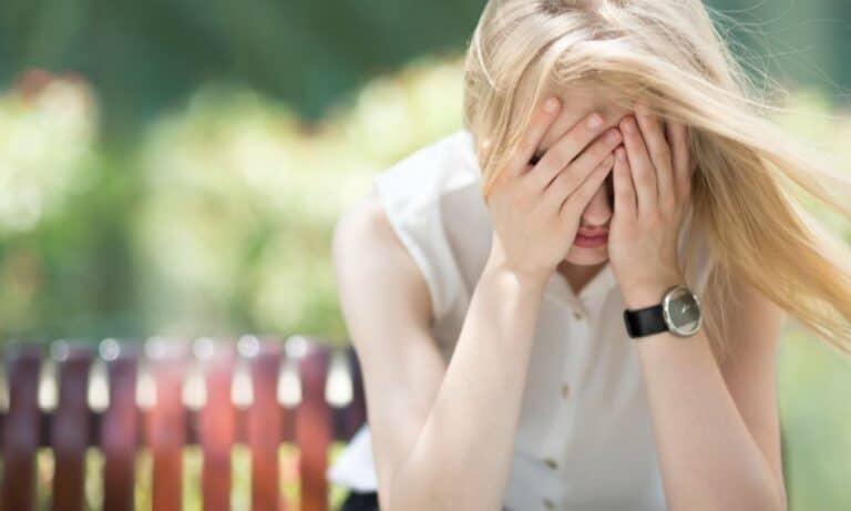 Woman on bench with hands over face