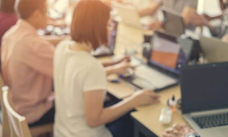 Employees gathered around large table desk in office