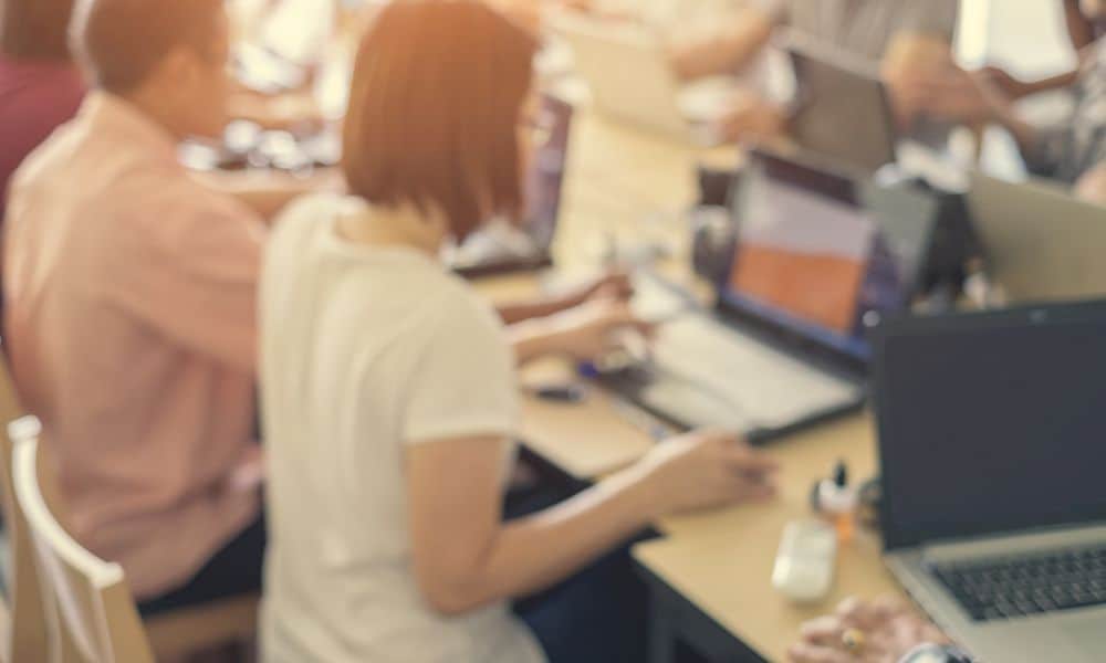 Employees gathered around large table desk in office