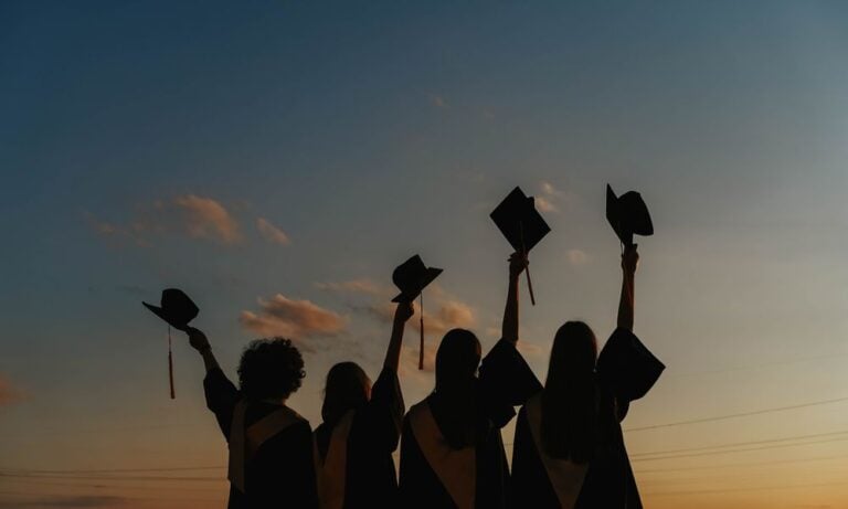 College graduates lifting their graduation caps.