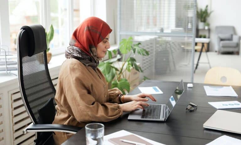 Photo of an employee typing at a desk on a laptop.