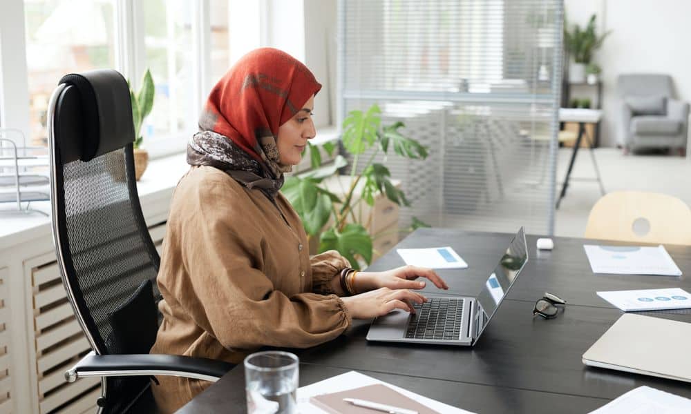 Photo of an employee typing at a desk on a laptop.
