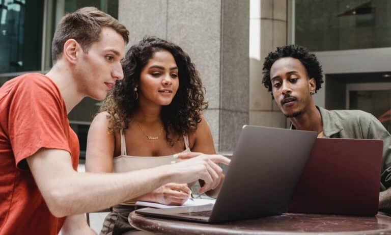 Employees pointing at laptop screens.