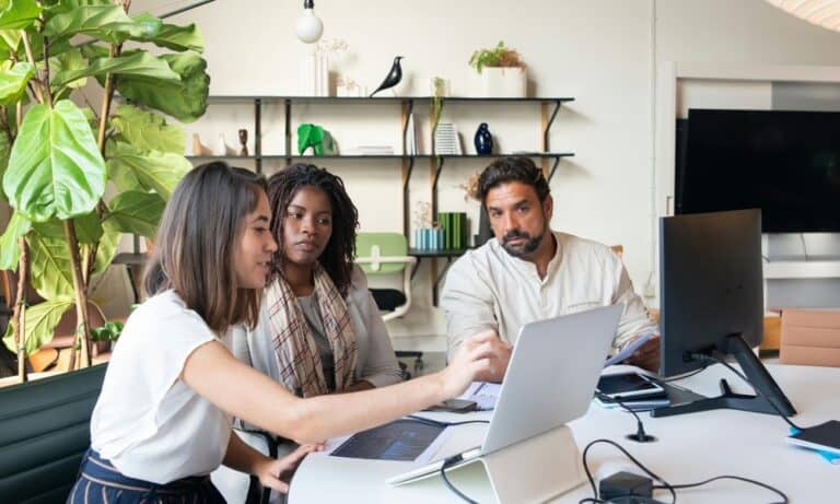 Employees sitting at a table with laptops.