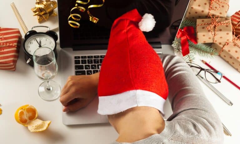 Employee in Santa hat rests head on computer