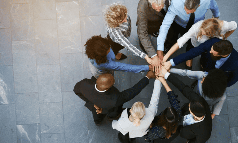 Photo of a team joining hands in a circle.