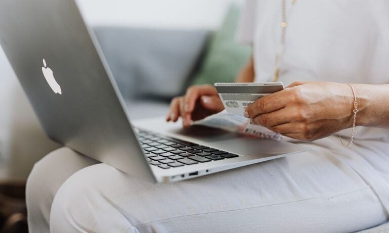 Person typing at a laptop while holding a credit card.