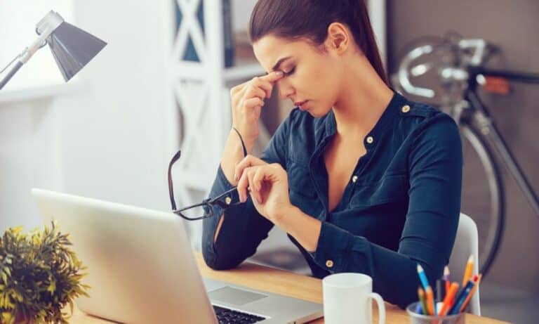 Stressed Employee Rubbing Eyes At Desk