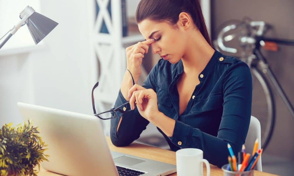 Stressed Employee Rubbing Eyes At Desk