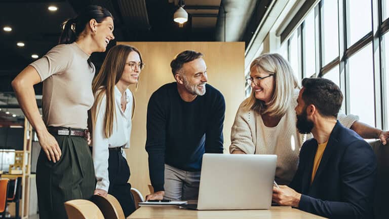 Photo of five coworkers in a meeting in a casual office setting