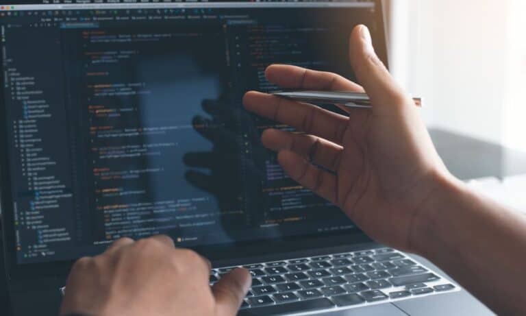 Hand with pen gesturing to computer screen