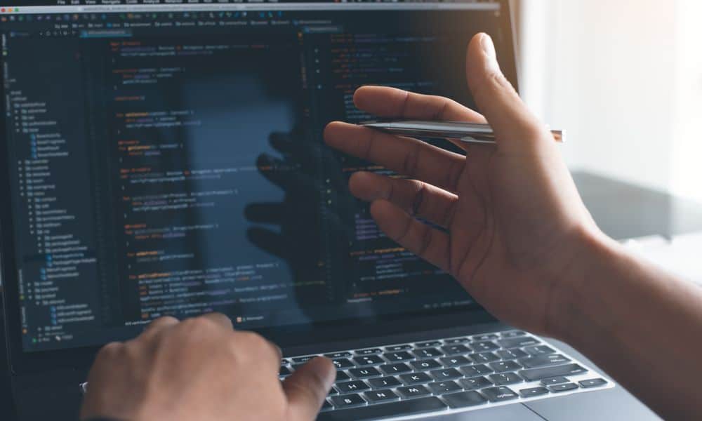 Hand with pen gesturing to computer screen