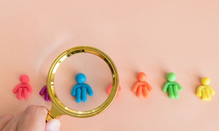 Photo of a magnifying glass and clay people to represent recruitment efforts.