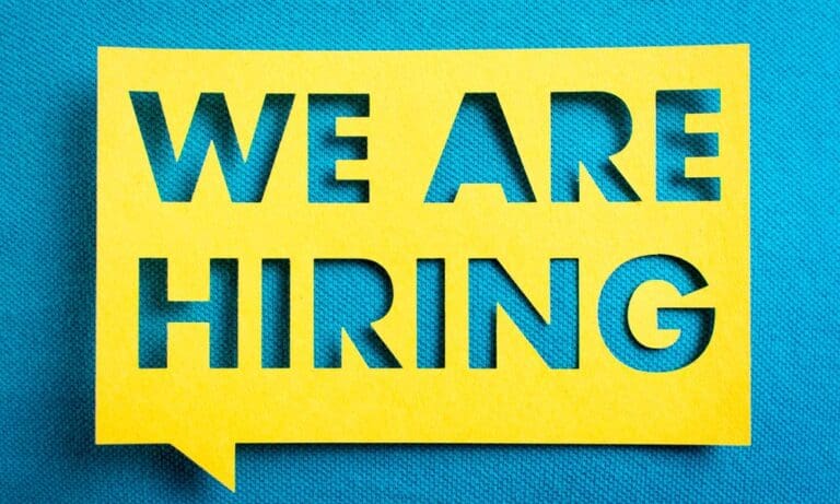 Photo of "We Are Hiring" in a cutout piece of paper.