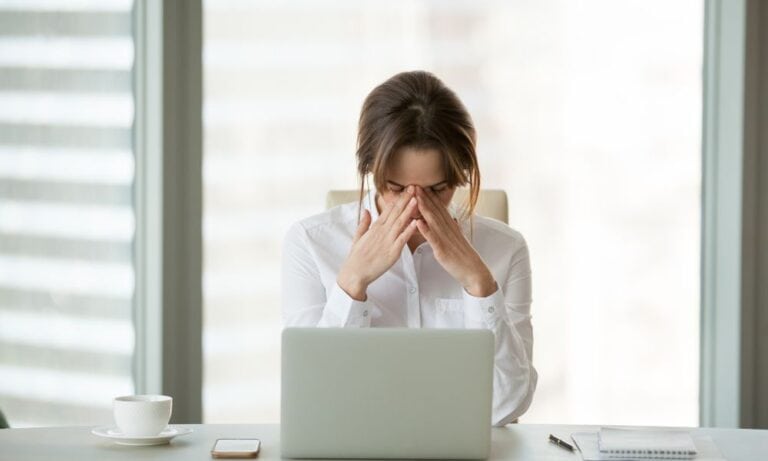 Woman rubbing forehead at work due to stress