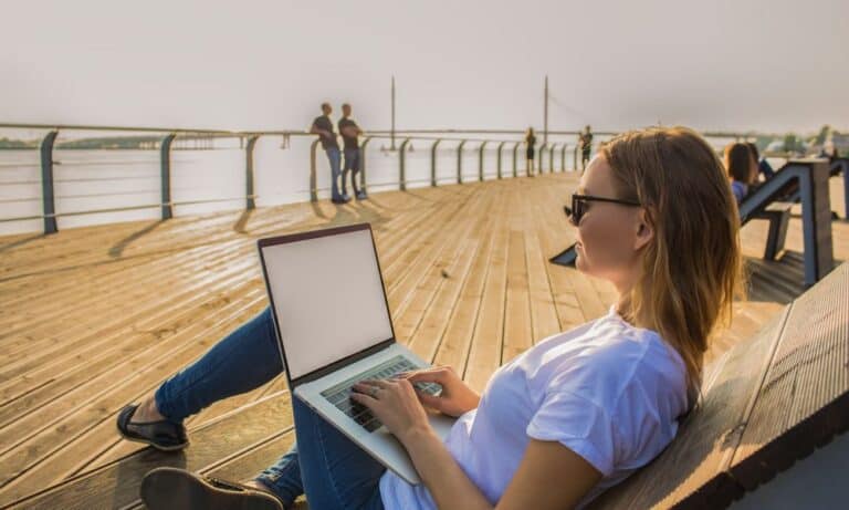 Woman working remotely from beach on laptop