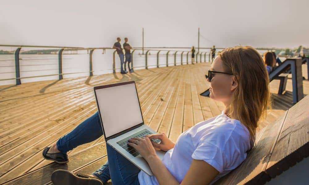 Woman working remotely from beach on laptop