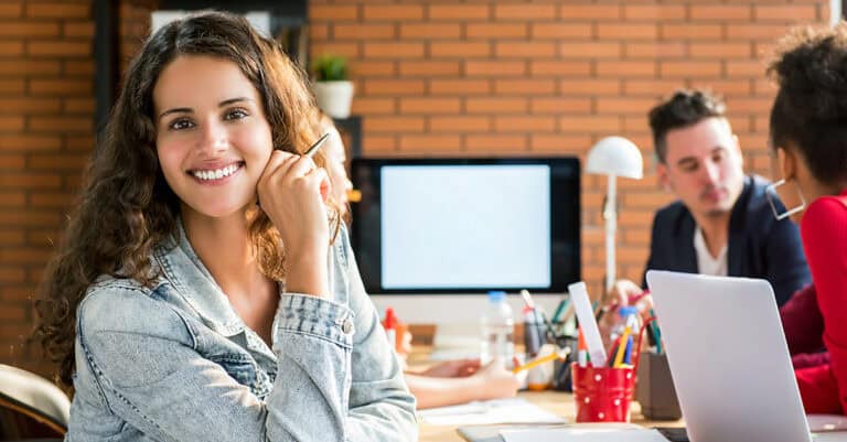 Team of creatives at desks, one smiling at camera