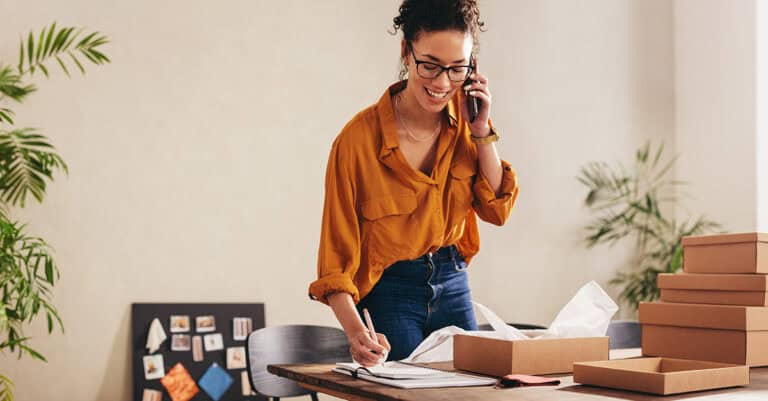 Woman on phone while writing in a notebook