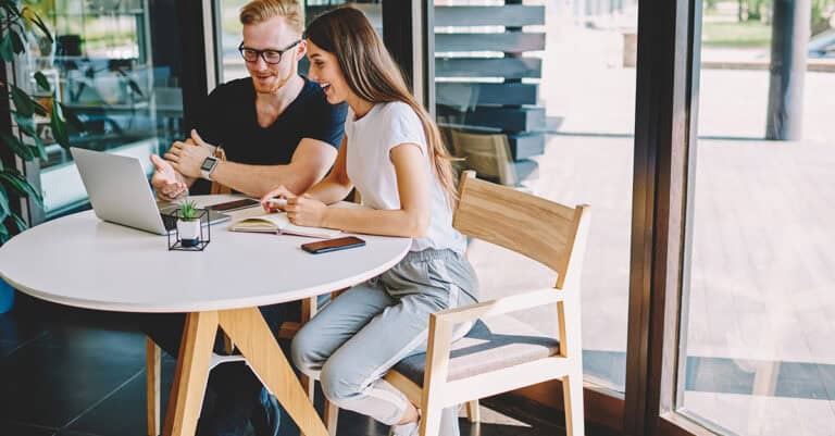 Coworkers in cafe, working on laptop together